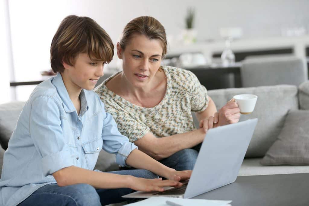 A son and his mother checking on their assignments for the day in the Homeschool Planet planner.